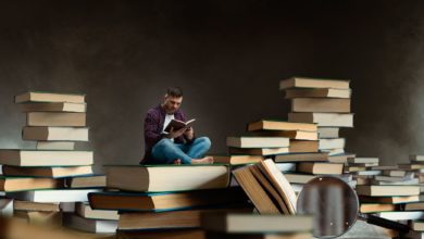 man setting between lot of books to self help